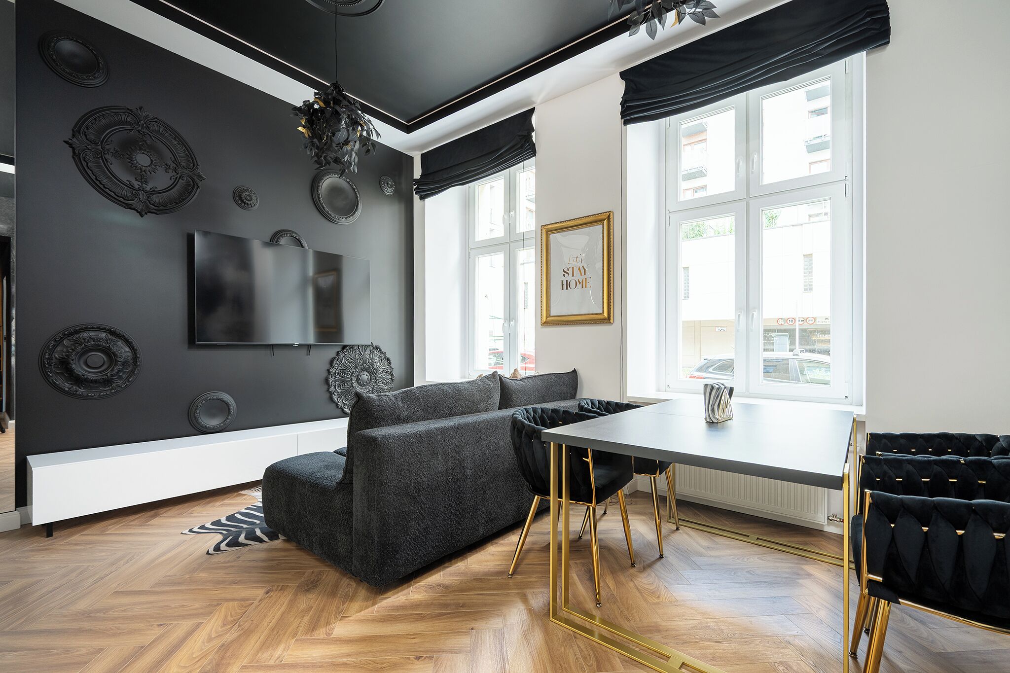 A modern living room with a sofa, a dining table, and a TV mounted on the wall.