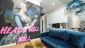 A modern living room with a large wall mural, a blue sofa, and a gold coffee table. - RentPlanet - Apartamenty Kilińskiego (Łódź)
