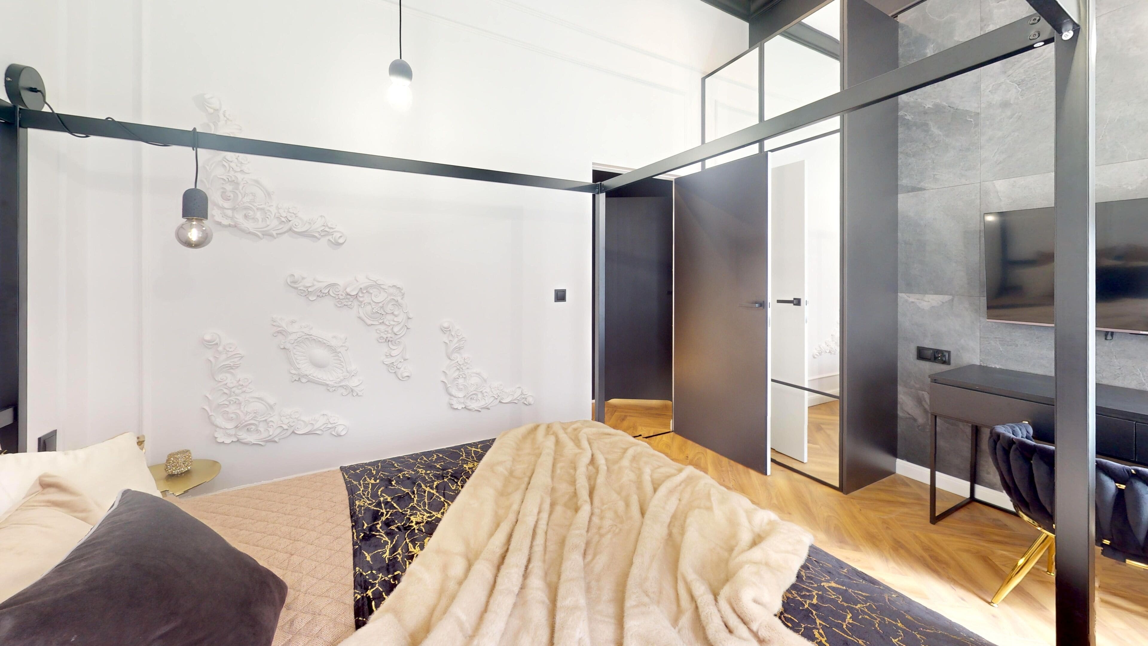 A modern bedroom with a bed, decorative wall, and a view of a dining area.