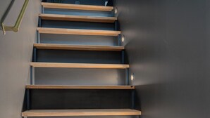 A staircase with wooden steps and metal railings. - RentPlanet - Apartamenty Kilińskiego (Łódź)