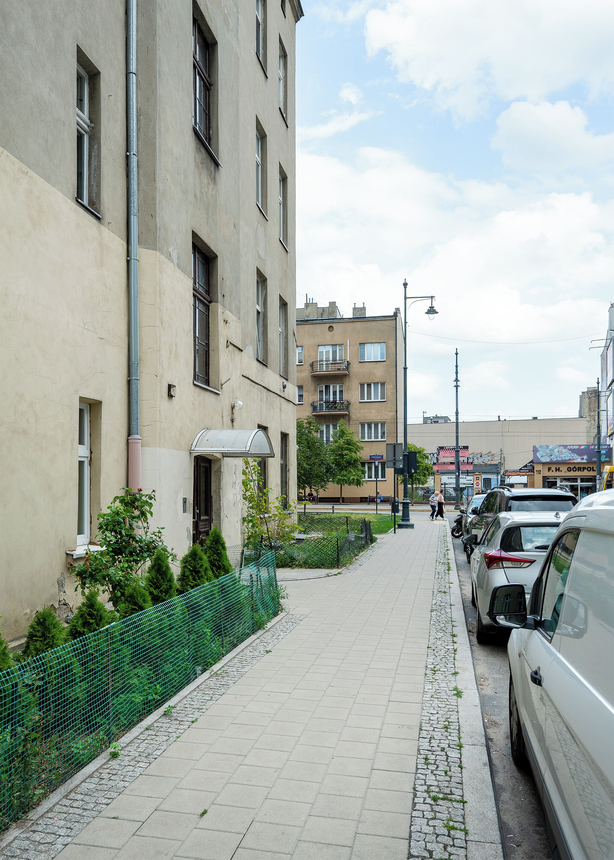 A street view with a sidewalk, parked cars, and buildings.