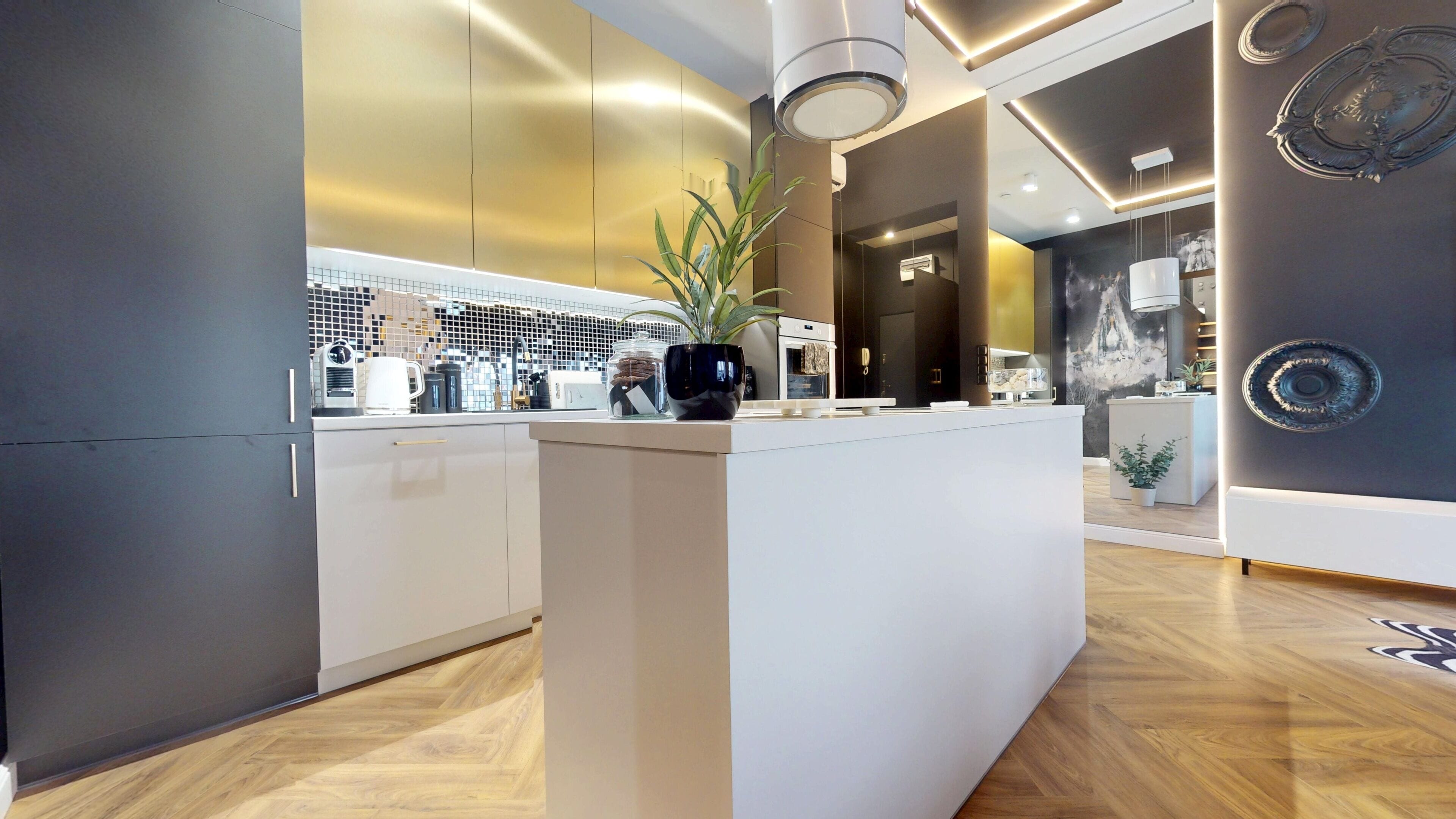 A modern kitchen with a central island, wooden flooring, and a decorative wall.