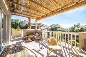 Eine überdachte Terrasse im Freien mit einer Couch, Stühlen und einem Essbereich.