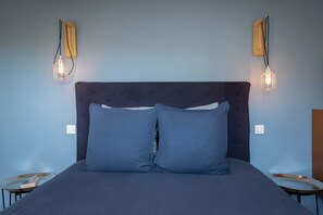 Ein Bett mit dunklem Kopfteil und zwei Kissen, dazu gehören zwei Nachttische mit Lampen.