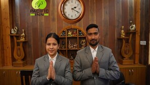 Two individuals in suits seated at a table with a clock and decorative items in the background. - Pacific Inn Prakrti the nature Lansdowne (Lansdowne)