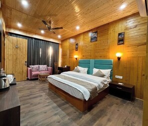 A bedroom with a wooden ceiling, a bed with a teal headboard, a pink sofa, and a small table.