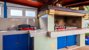An outdoor kitchen with a gas stove, a grill, and blue cabinets. - Gorgeous apartment in Valbandon with WiFi (Valbandon)