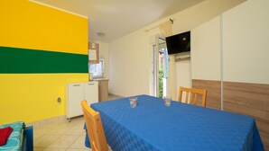 A room with a blue table, two chairs, a small kitchenette, a television, and a window with curtains. - Gorgeous apartment in Valbandon with WiFi (Valbandon)