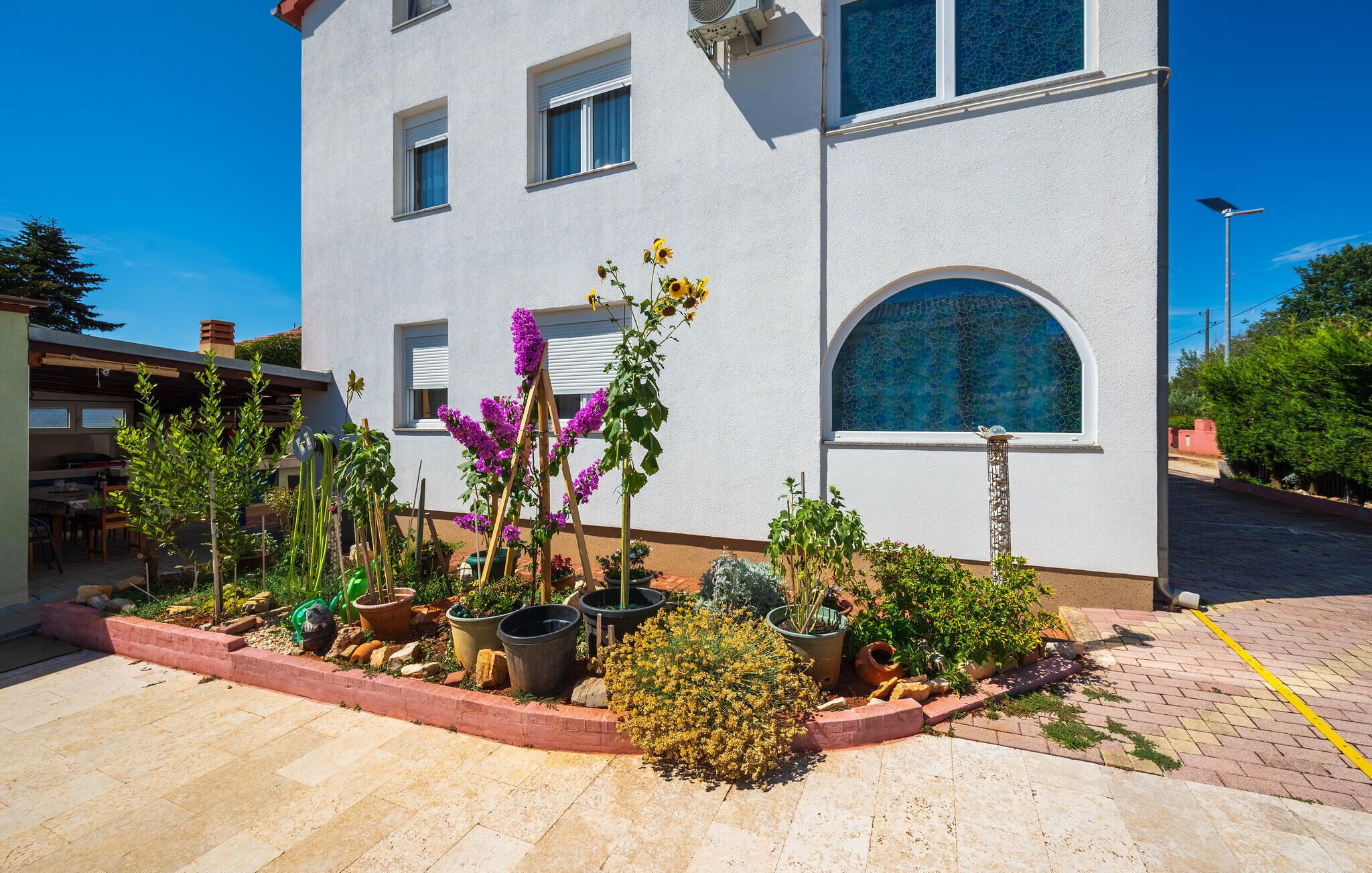 A building with a garden in front, including potted plants and flowers.