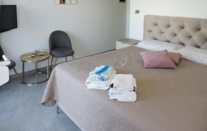 A hotel room with a bed, a chair, a small table, and a bedside table with a lamp. - Nice apartment in Peroj with WiFi (Peroj)