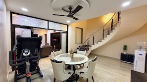 Un soggiorno moderno con tapis roulant, un'area da pranzo con tavolo rotondo e una scala.
