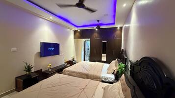 A bedroom with a bed, a television, a ceiling fan, and a wardrobe.