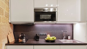 Una cocina con horno de acero inoxidable, hervidor de agua, frutero y bloque de cuchillos.