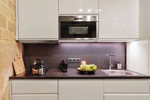 A kitchen with a stainless steel oven, a kettle, a fruit bowl, and a knife block. - Cosy Studio Near Louvre & Les Halles (Paris)