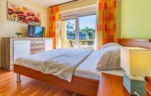A modern bedroom with a bed, a TV, a desk, and a balcony view. - Beautiful apartment in Medulin with WiFi (Medulin)