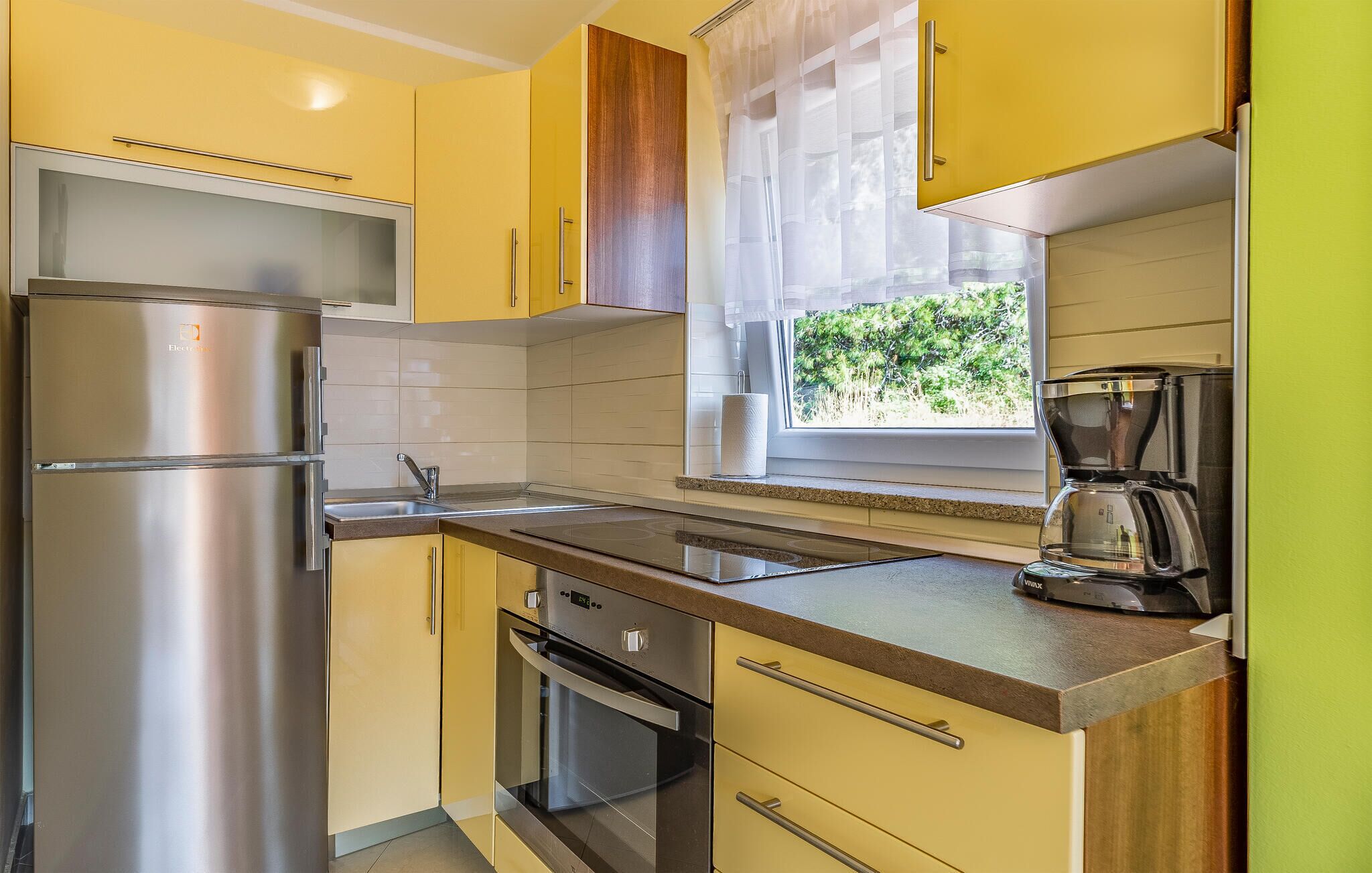 A compact kitchen with a refrigerator, oven, and coffee maker.