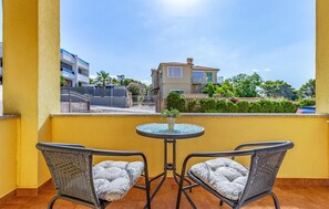 A balcony with two wicker chairs and a small table, overlooking a residential area with buildings and greenery. - Beautiful apartment in Medulin with WiFi (Medulin)
