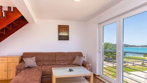 Ein Wohnzimmer mit einem braunen Ecksofa, einem Glastisch und einem Gemälde an der Wand.