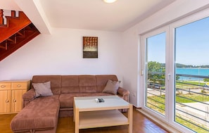 Ein Wohnzimmer mit einem braunen Ecksofa, einem Glastisch und einem Gemälde an der Wand.