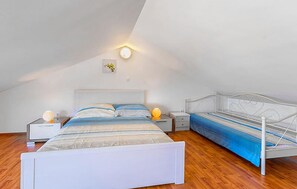 A bedroom with a sloped ceiling, a bed with a white frame, a bedside table with a lamp, and a wall-mounted light fixture. - Apartment in Medulin (758) (Medulin)
