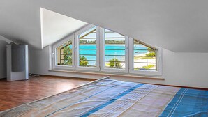 A room with a sloped ceiling, a large window with multiple panes, and a wooden floor. - Apartment in Medulin (758) (Medulin)