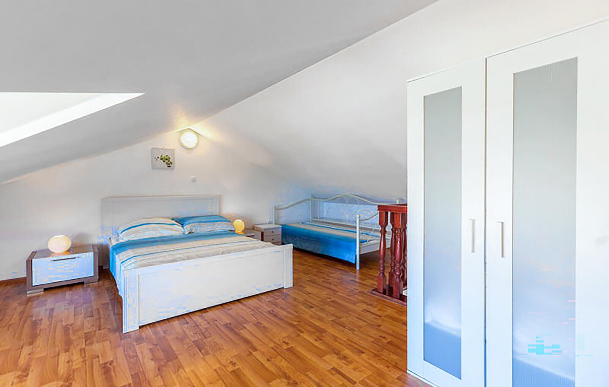 Um quarto com teto inclinado, uma cama com cabeceira, mesas de cabeceira e um guarda-roupa.