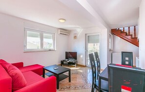 A living room with a red sofa, a black table, and a TV. There is a staircase leading to another level. - Apartment in Medulin (760) (Medulin)