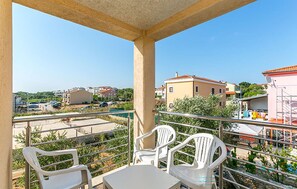 A balcony with a table and chairs, overlooking a parking area and buildings. - Apartment in Medulin (760) (Medulin)