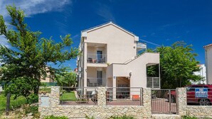 A two-story building with a balcony, a stone wall in front, and a red car parked nearby. - Apartment in Medulin (760) (Medulin)