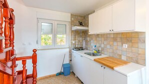 A compact kitchen with white cabinets, a wooden countertop, a window with a view, and a tiled backsplash. - Apartment in Medulin (760) (Medulin)