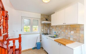 A compact kitchen with white cabinets, a wooden countertop, a window with a view, and a tiled backsplash. - Apartment in Medulin (760) (Medulin)