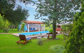 A poolside area with lounge chairs, a small building with a tiled roof, and a barbecue grill. - Gorgeous apartment in Trget (Trget)