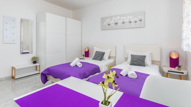 A hotel room with two beds, a large mirror, a painting, and a small table with a lamp. - Beautiful apartment in Pula (Pula)