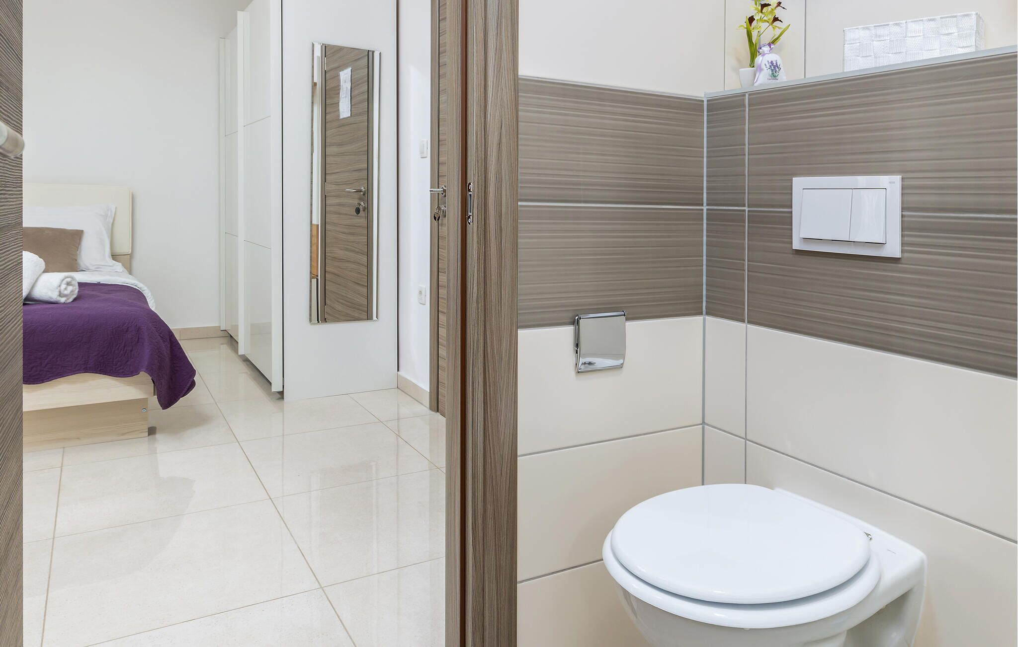 A hotel room with a bed, a bathroom with a toilet, and a shower area.