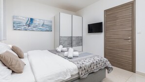 A bedroom with a bed, a TV, a wardrobe, and a painting on the wall. - Beautiful apartment in Pula with WiFi (Pula)
