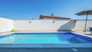 A swimming pool with a clear blue water surface, a white wall, and a tiled roof in the background. - Awesome apartment in Galizana with WiFi (Galizana)