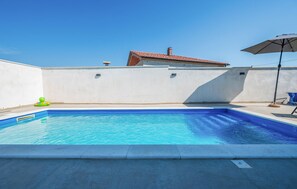 A swimming pool with a clear blue water surface, a white wall, and a tiled roof in the background. - Awesome apartment in Galizana with WiFi (Galizana)