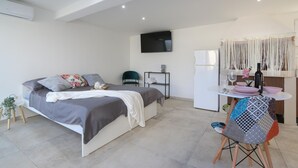 A modern bedroom with a bed, a small table, a chair, a TV, and a refrigerator. - Awesome apartment in Galizana with WiFi (Galizana)