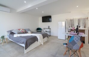 A modern bedroom with a bed, a small table, a chair, a TV, and a refrigerator. - Awesome apartment in Galizana with WiFi (Galizana)