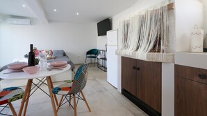 A modern kitchen with a dining area, featuring a white table, a colorful chair, and a wooden cabinet. - Awesome apartment in Galizana with WiFi (Galizana)