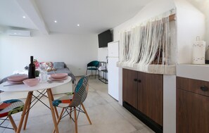 A modern kitchen with a dining area, featuring a white table, a colorful chair, and a wooden cabinet. - Awesome apartment in Galizana with WiFi (Galizana)