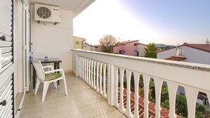 A balcony with a table and chairs, a white railing, and a view of neighboring buildings. - Amazing apartment in Pula with WiFi (Pula)