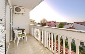 Ein Balkon mit Tisch und Stühlen, einem weißen Geländer und Blick auf die Nachbargebäude.