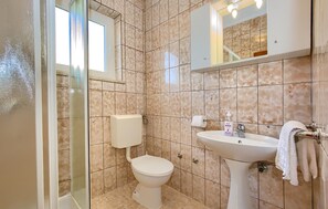 Ein Badezimmer mit Toilette, Waschbecken und einer Duschkabine aus Glas.