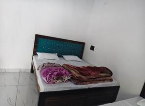 A bed with a teal headboard, white pillows, and a brown blanket. - Shaaneshwar Mahadev Hotel & Restaurant (Ukhimath)