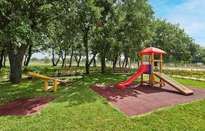 A playground with a slide and swings, surrounded by trees and grass. - Stunning apartment in Umag with swimming pool (Umag)