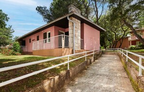 A single-story building with a red exterior, a white railing along a concrete pathway leading to the entrance, and a stone chimney. - Stunning apartment in Umag with swimming pool (Umag)