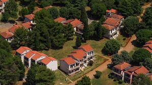 Oversigtsbillede af et boligområde med flere huse, rødlægte og grøn beplantning.