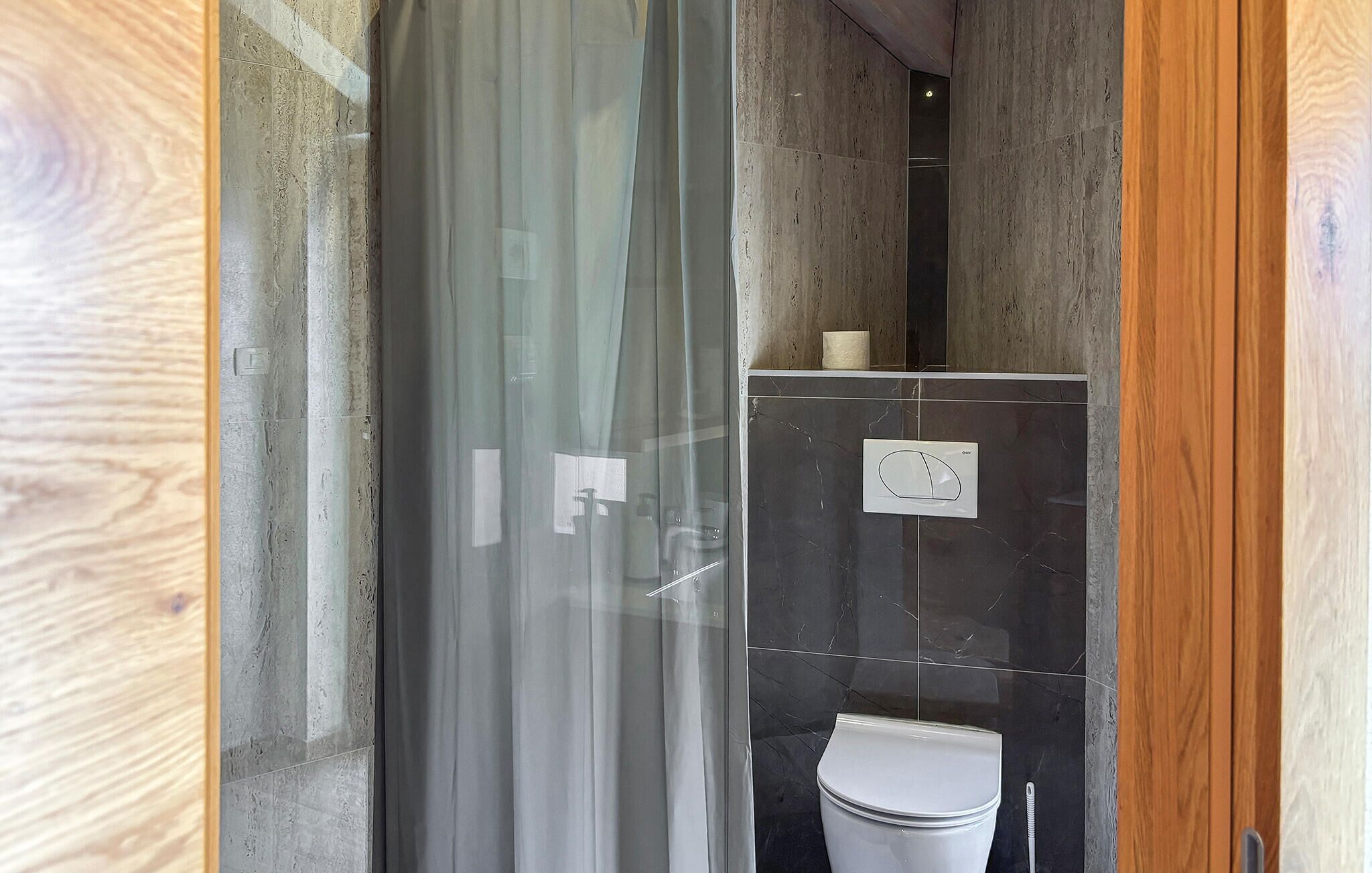 Un baño con cabina de ducha de vidrio, inodoro y dispensador de toallas.