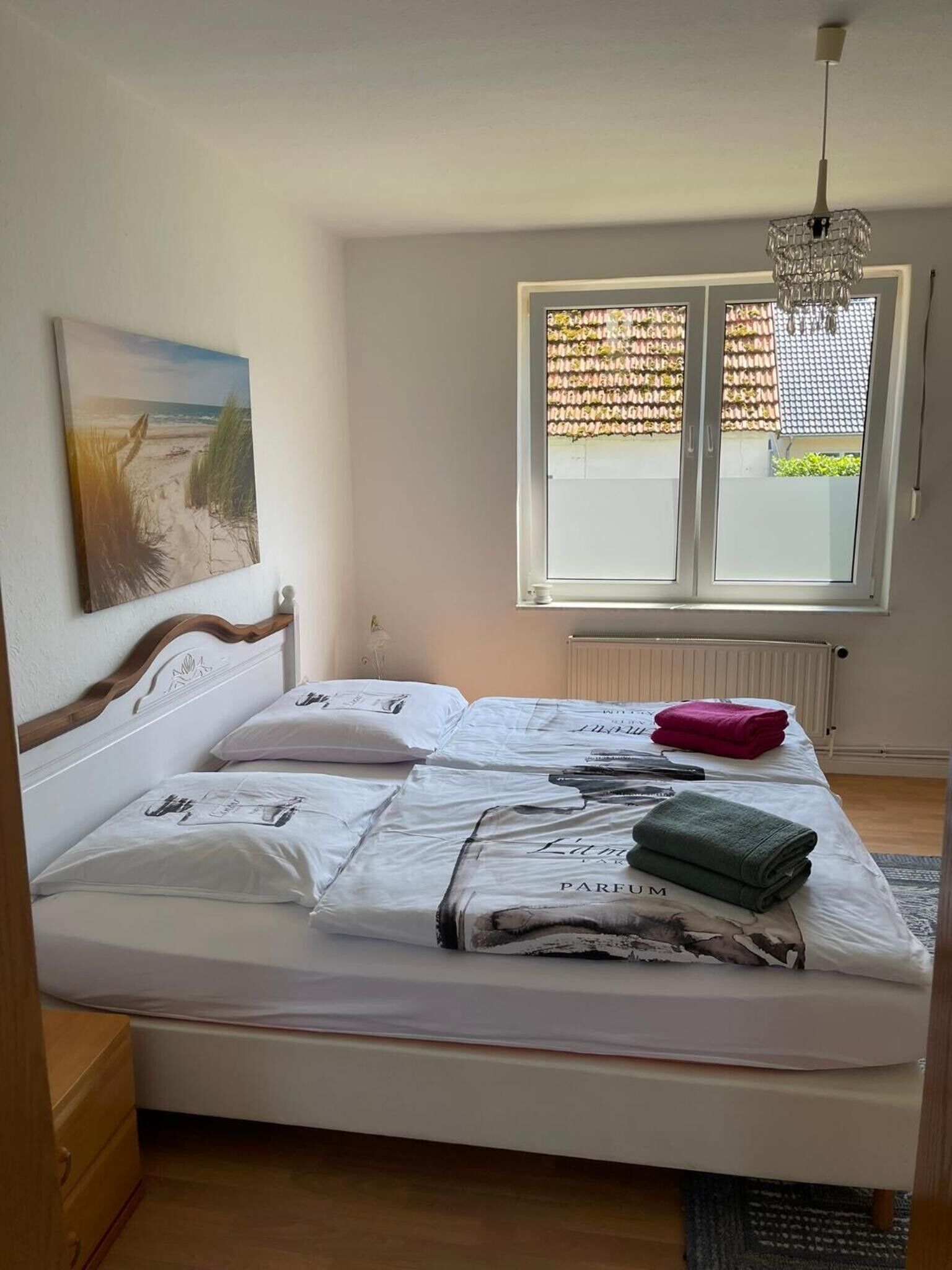 Una camera da letto con un letto, una finestra con persiane, un termosifone e un quadro appeso al muro.